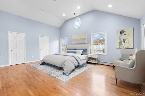 a spacious bedroom with a bed a couch and a window with wooden floor