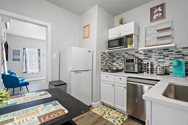 a kitchen with stainless steel appliances a stove a refrigerator sink and white cabinets