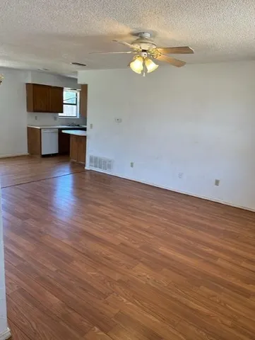 a view of kitchen and empty room with wooden floor