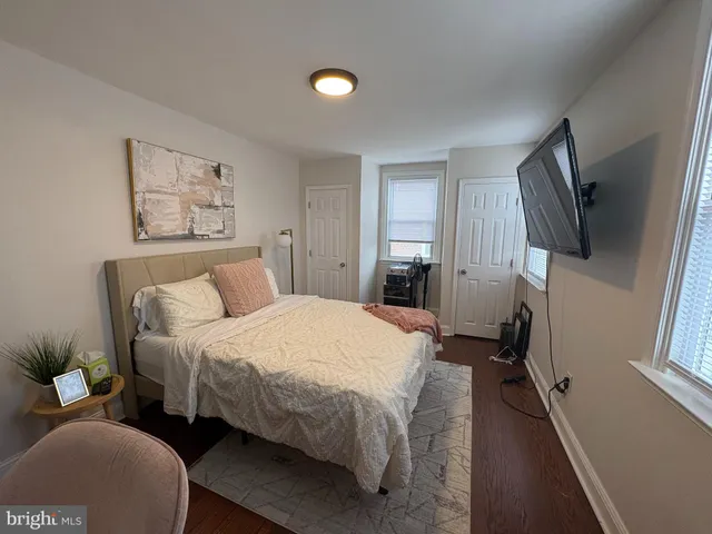 a bedroom with a bed a mirror on dresser and a window