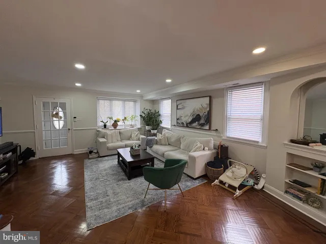 a living room with furniture large window and wooden floor