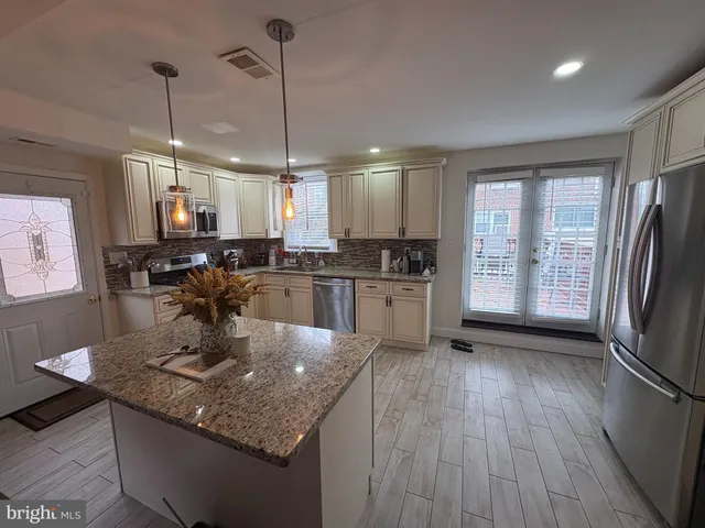 a kitchen with stainless steel appliances granite countertop wooden floors sink stove and refrigerator