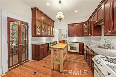 a kitchen with stainless steel appliances granite countertop a stove top oven a sink dishwasher a dining table and chairs with wooden floor