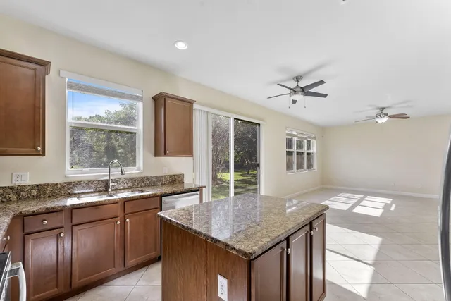 a kitchen with stainless steel appliances kitchen island granite countertop a refrigerator a sink a stove and white cabinets