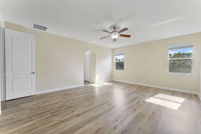 an empty room with wooden floor and windows
