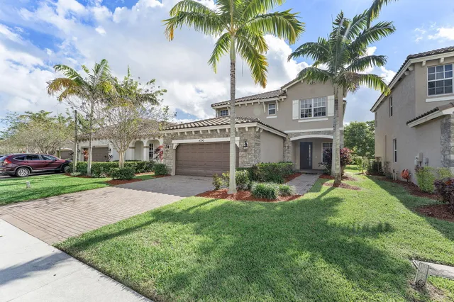 a front view of a house with a garden and tree