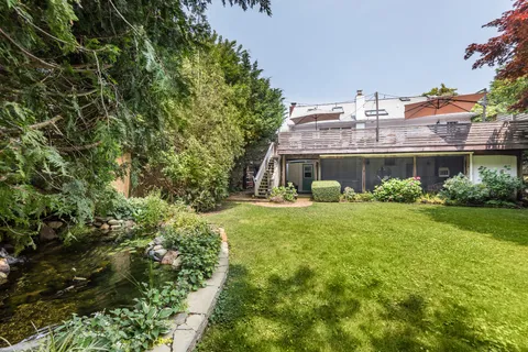 a front view of a house with a yard and a large tree