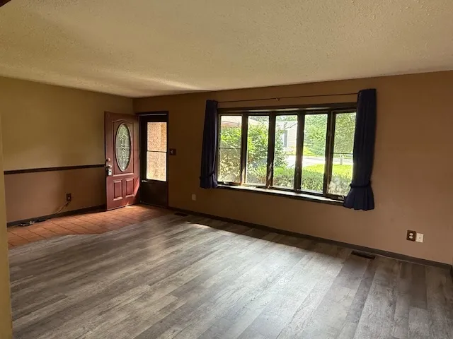 a view of an empty room with a window and wooden floor