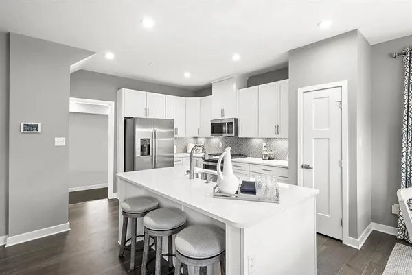 a kitchen with stainless steel appliances a dining table chairs and wooden floor