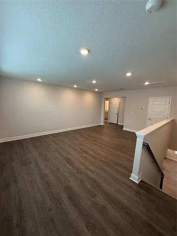 an empty room with wooden floor and staircase