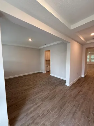 a view of an empty room with wooden floor and window