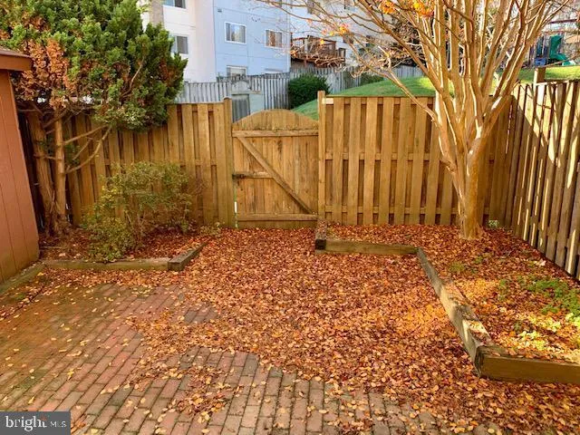 a view of backyard with wooden fence and large trees