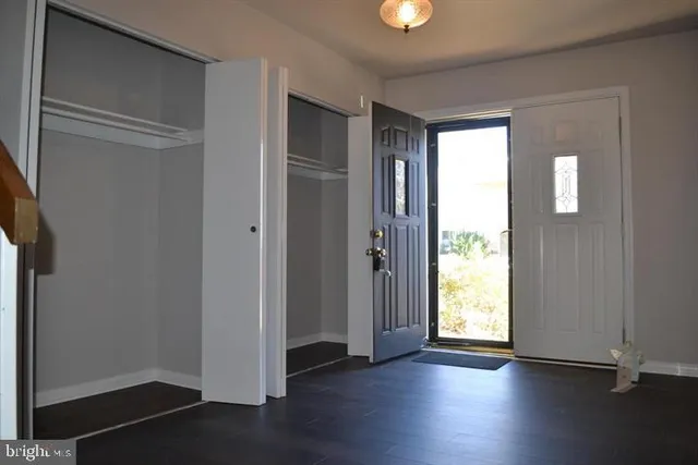 an empty room with wooden floor closet and windows