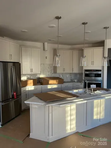 a kitchen with stainless steel appliances granite countertop a sink a stove a refrigerator a center island a stove and cabinets