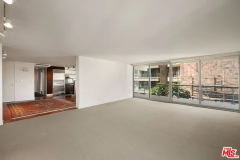 a view of a big room with windows and chandelier fan