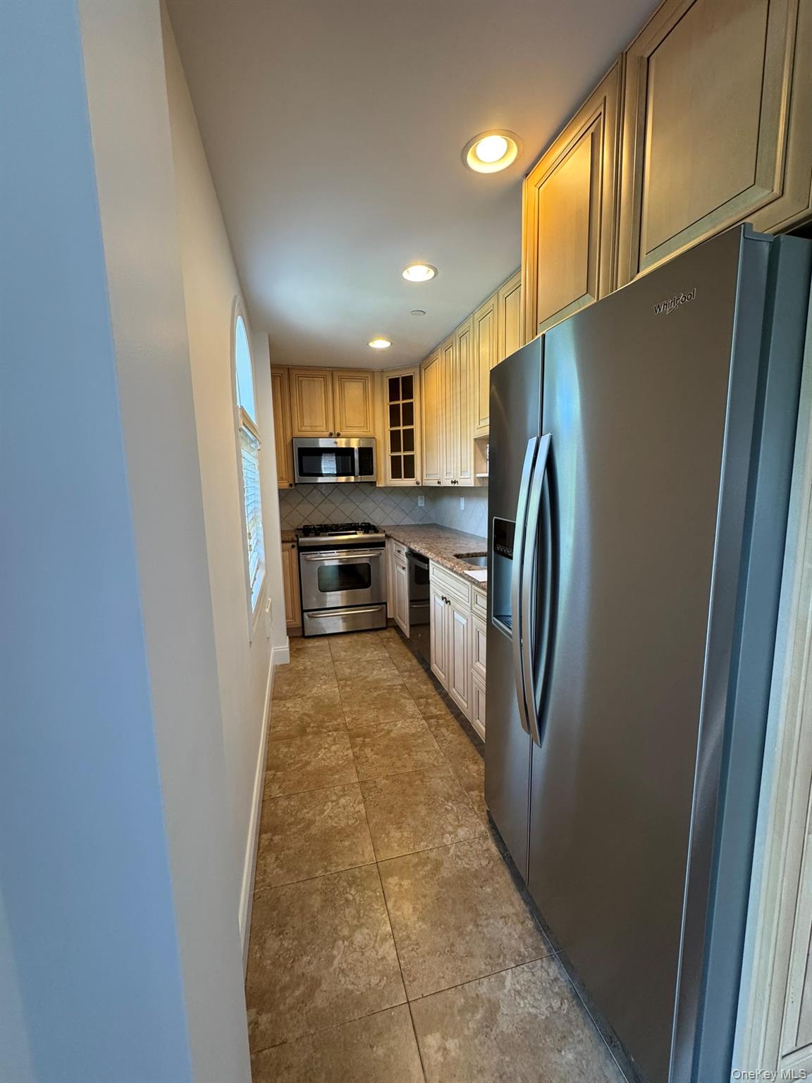 42-23 212th Street, Unit 3C Queens, NY 11361 - Photo 5 of 13 Kitchen with stainless steel appliances, decorative backsplash, recessed lighting, glass insert cabinets, and tile patterned floors