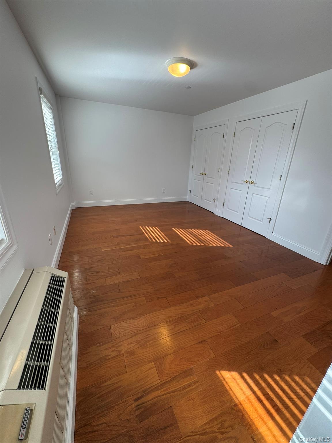 42-23 212th Street, Unit 3C Queens, NY 11361 - Photo 7 of 13 Unfurnished bedroom with multiple closets, baseboards, and wood finished floors