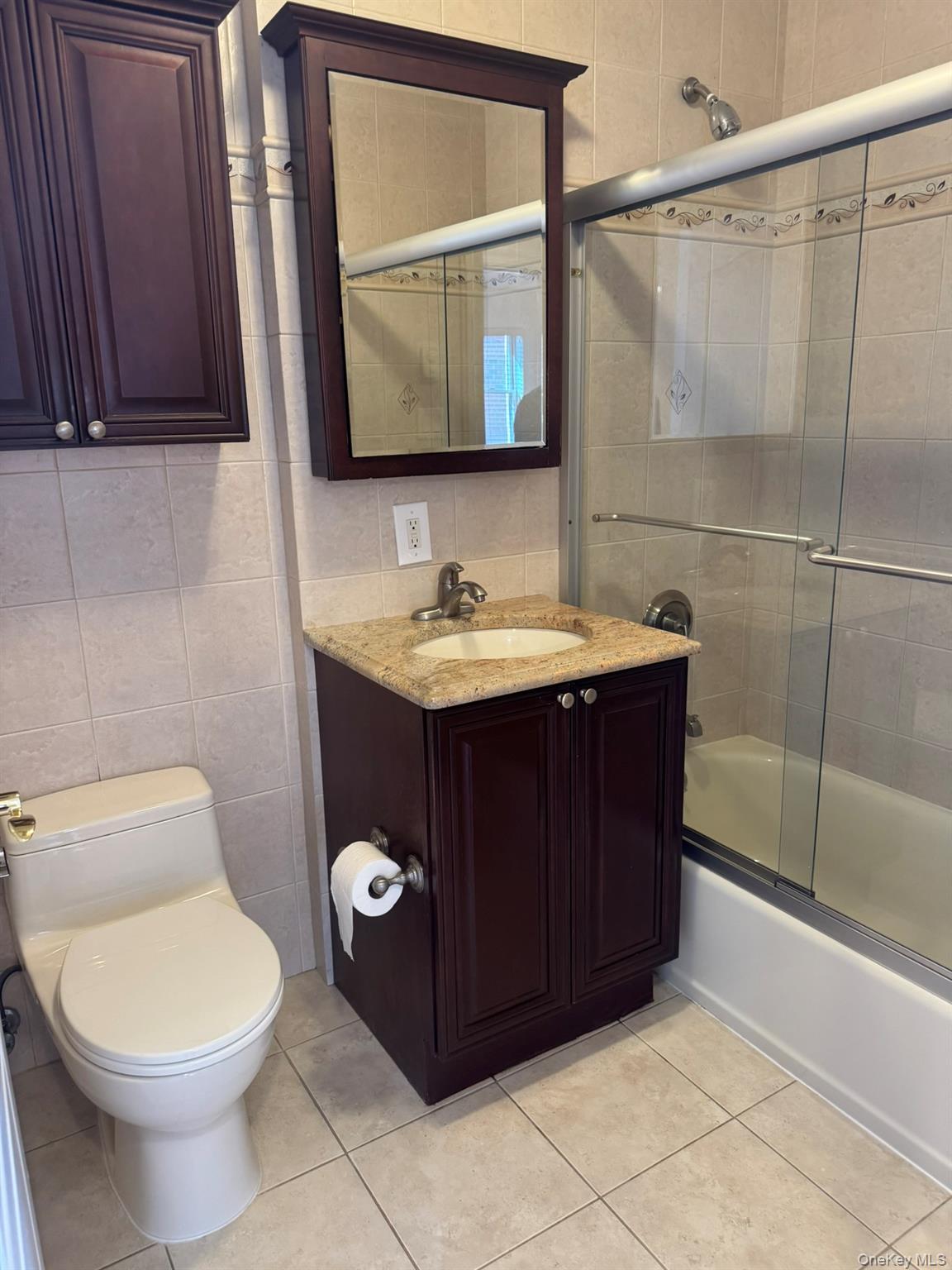 42-23 212th Street, Unit 3C Queens, NY 11361 - Photo 8 of 13 Full bath featuring tile walls, tile patterned floors, shower / bath combination with glass door, toilet, and vanity