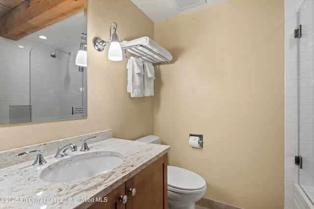 a bathroom with a granite countertop sink a toilet and a mirror