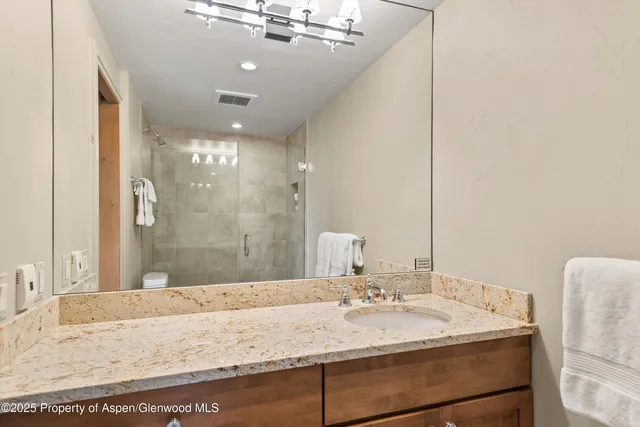 a bathroom with a granite countertop sink a mirror and shower