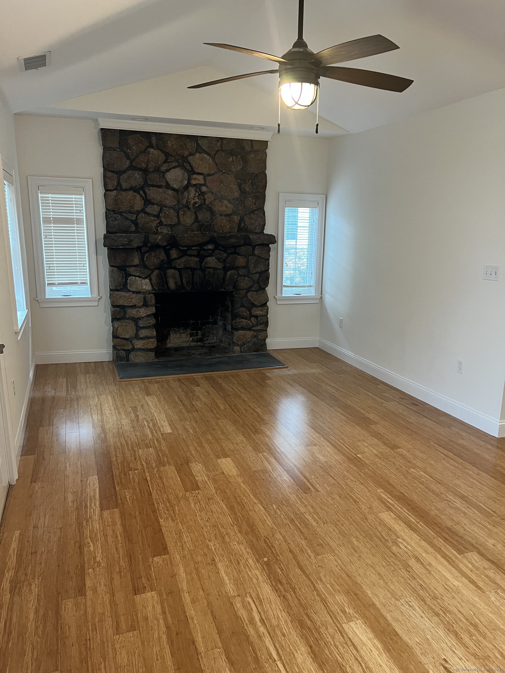 170 Shore Road Clinton, CT 06413 - Photo 5 of 20 an empty room with wooden floor fireplace and windows