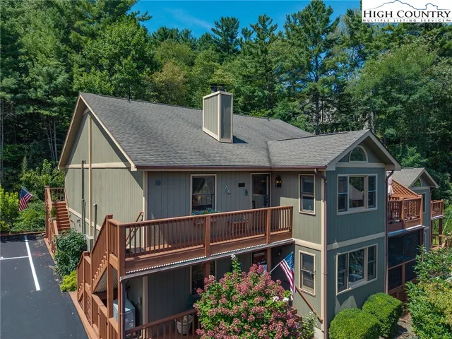 a view of a house with wooden deck and outdoor seating