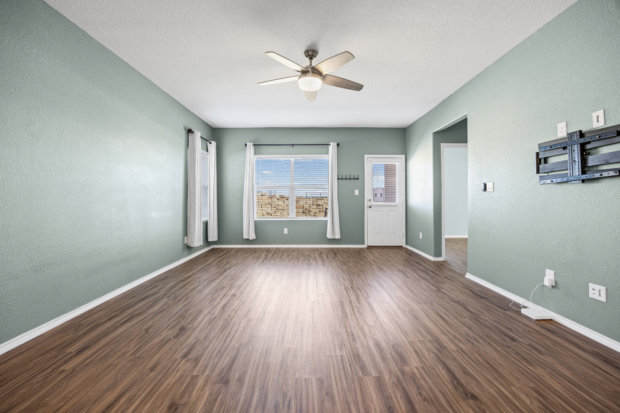1609 Woolsey Way Leander, TX 78641 - Photo 10 of 29 an empty room with wooden floor chandelier fan and windows