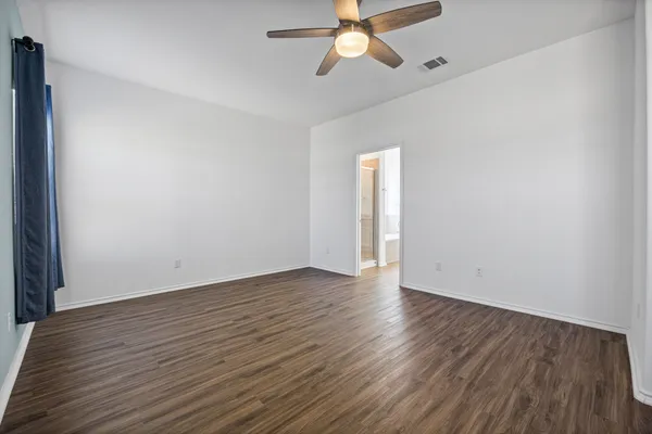 a view of a room with wooden floor and a ceiling fan
