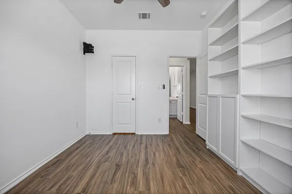 a view of a hallway with wooden floor and a cabinet