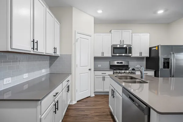 a kitchen with stainless steel appliances granite countertop a sink stove microwave and refrigerator