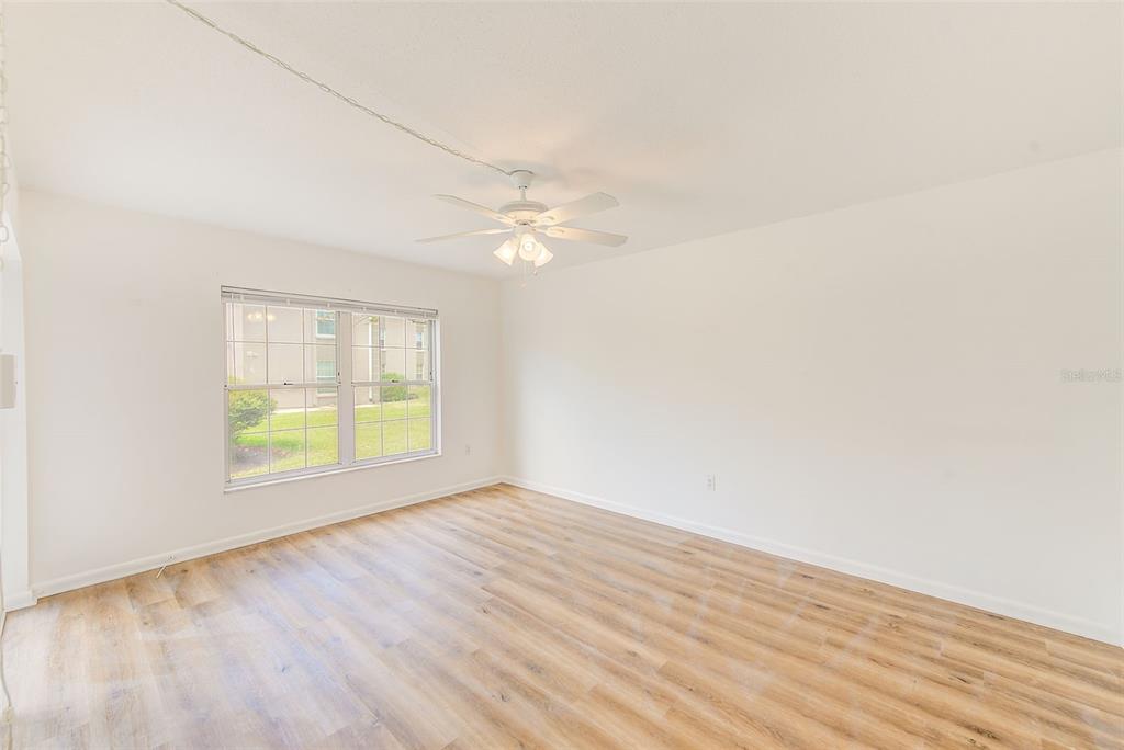 10280 Imperial Point Drive West, Unit 7 Largo, FL 33774 - Photo 34 of 67 an empty room with wooden floor and windows
