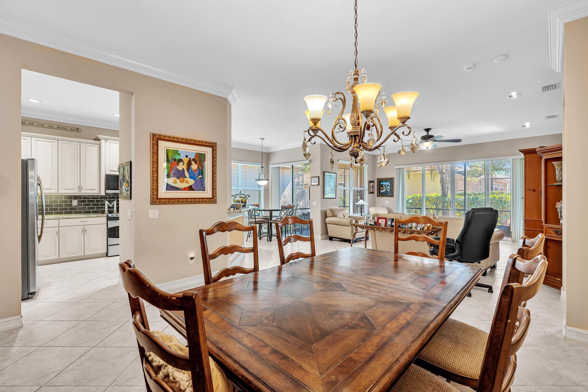 9062 Meridian View Isle Boynton Beach, FL 33473 - Photo 20 of 71 a dining room with wooden floor a chandelier a glass table and chairs