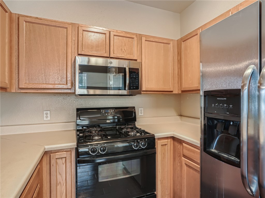 13913 Harris Ridge Boulevard, Unit B Pflugerville, TX 78660 - Photo 12 of 25 a kitchen with stainless steel appliances granite countertop a stove a microwave and a refrigerator