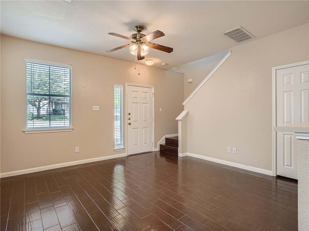 13913 Harris Ridge Boulevard, Unit B Pflugerville, TX 78660 - Photo 7 of 25 an empty room with wooden floor chandelier fan and windows