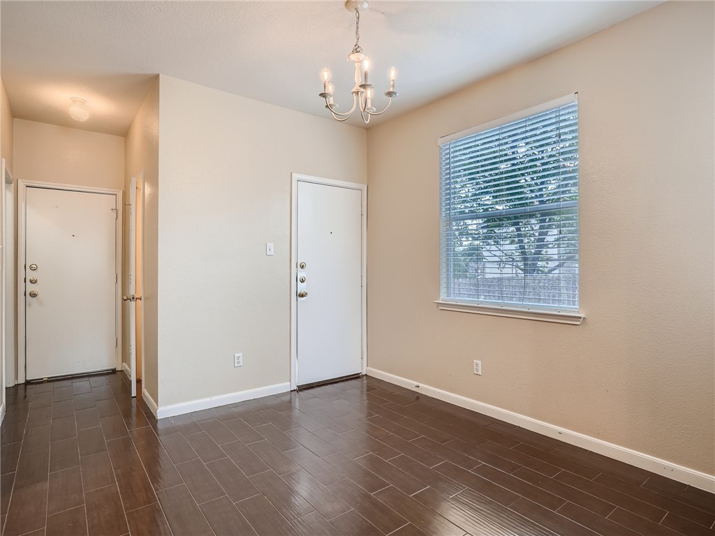 13913 Harris Ridge Boulevard, Unit B Pflugerville, TX 78660 - Photo 8 of 25 an empty room with wooden floor chandelier and windows