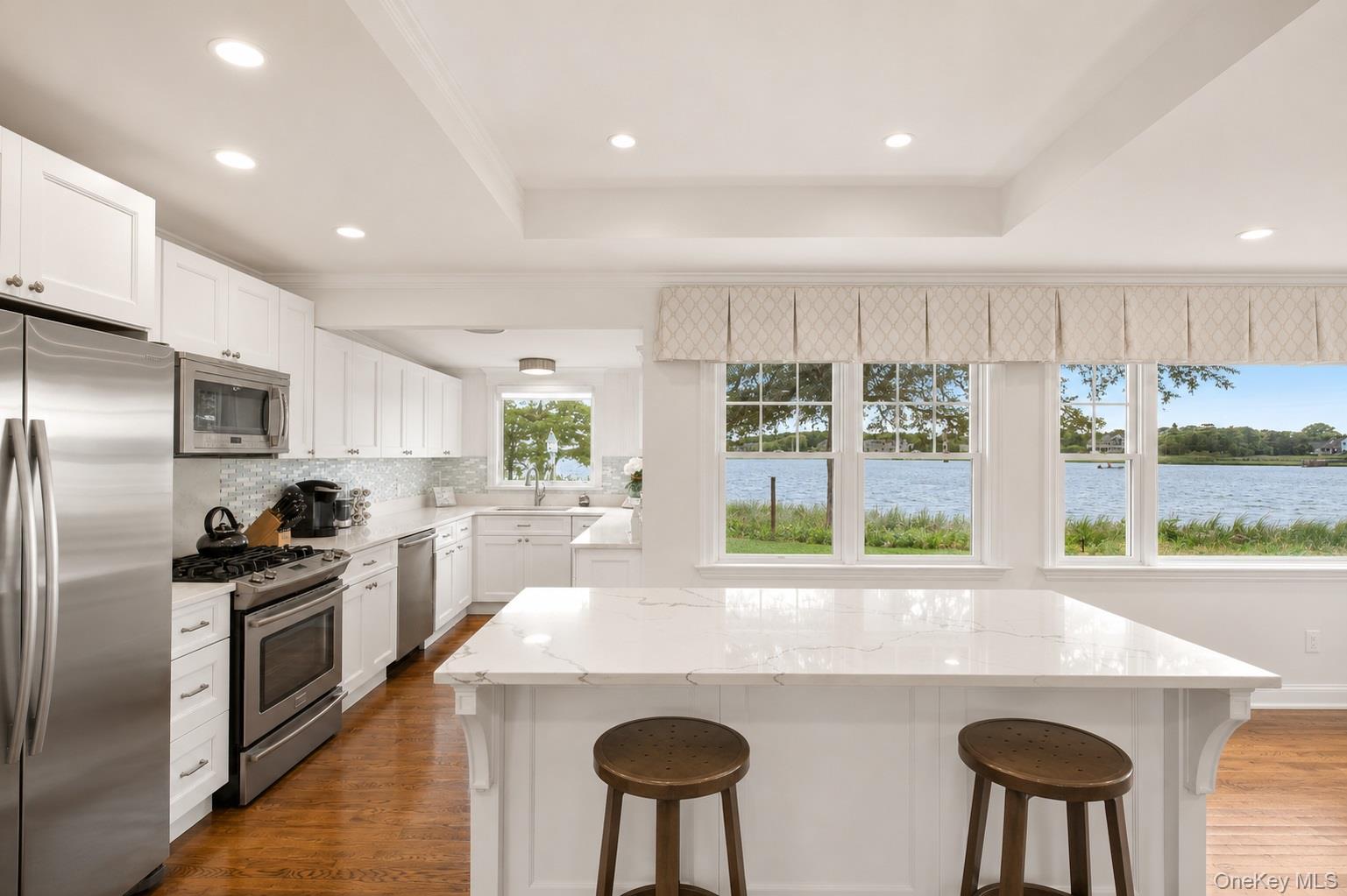 65 Shore Road Westhampton, NY 11977 - Photo 11 of 24 Kitchen featuring white shaker cabinetry, stainless steel appliances, and a mosaic tile backsplash