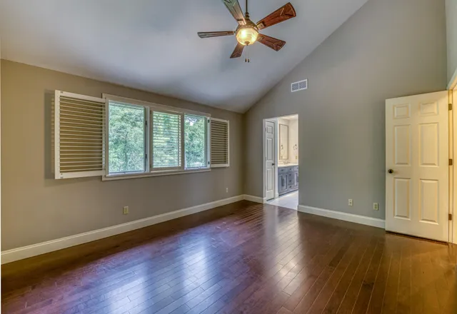 a view of an empty room with a window and wooden floor