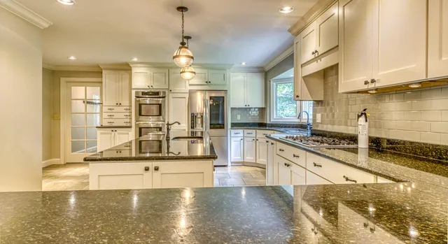 a large kitchen with granite countertop a stove a sink and a granite counter top