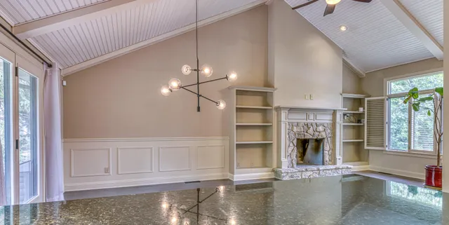 a view of empty room with wooden floor and kitchen view