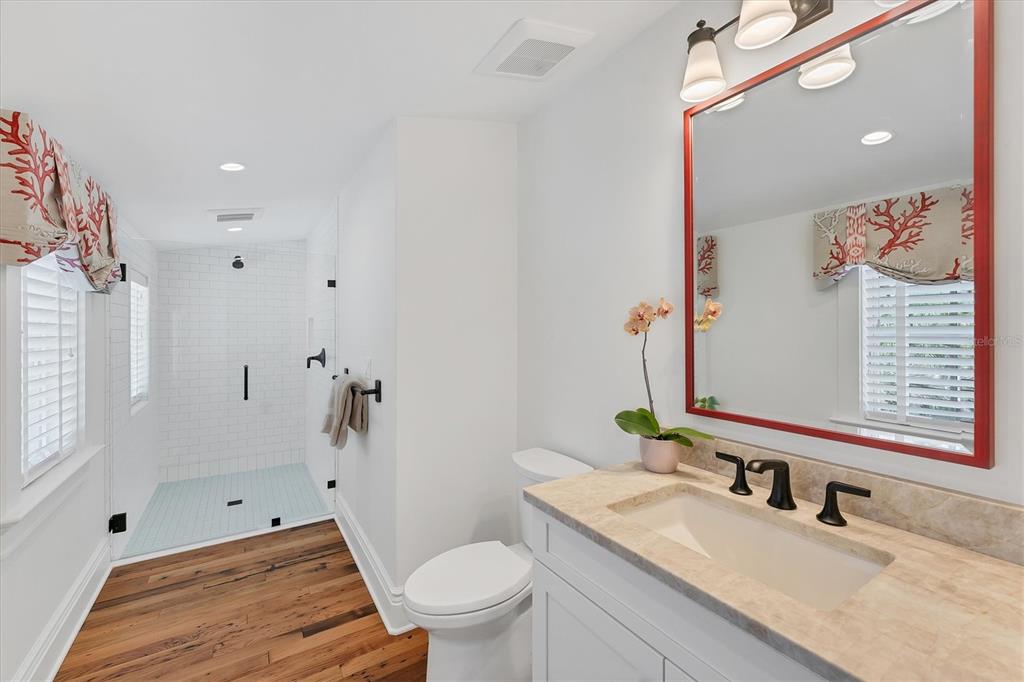 150 1st Street East Boca Grande, FL 33921 - Photo 41 of 72 a bathroom with a granite countertop sink a toilet a mirror a vanity and shower