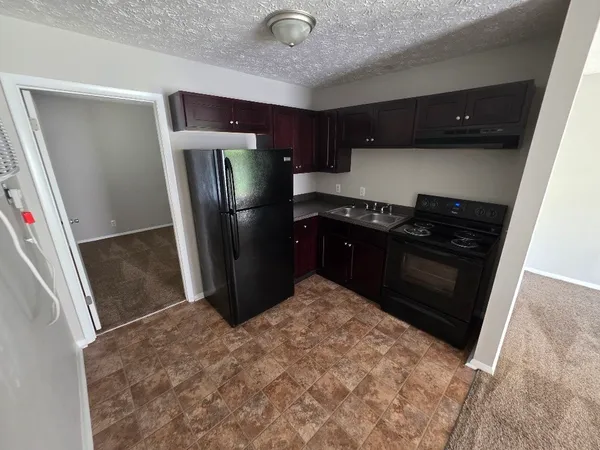 a kitchen with stainless steel appliances granite countertop a refrigerator a stove and a sink