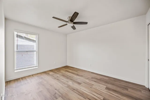 an empty room with wooden floor and ceiling fan
