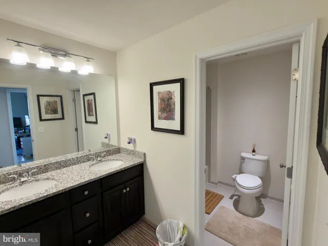 a bathroom with a granite countertop sink toilet and mirror