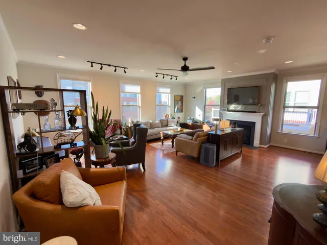 a living room with furniture kitchen view and a wooden floor
