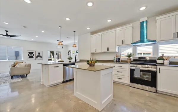 a kitchen that has a lot of white cabinets and stainless steel appliances
