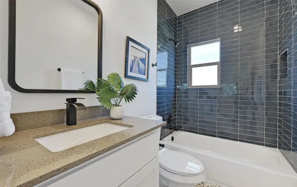 a bathroom with a granite countertop bathtub sink vanity mirror and toilet