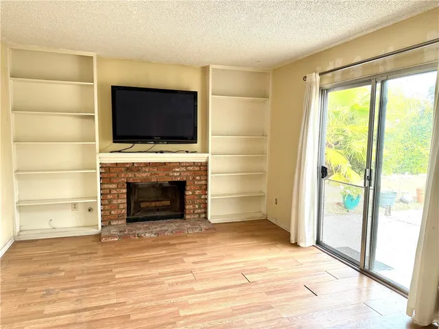 a view of an empty room with fire place and a window