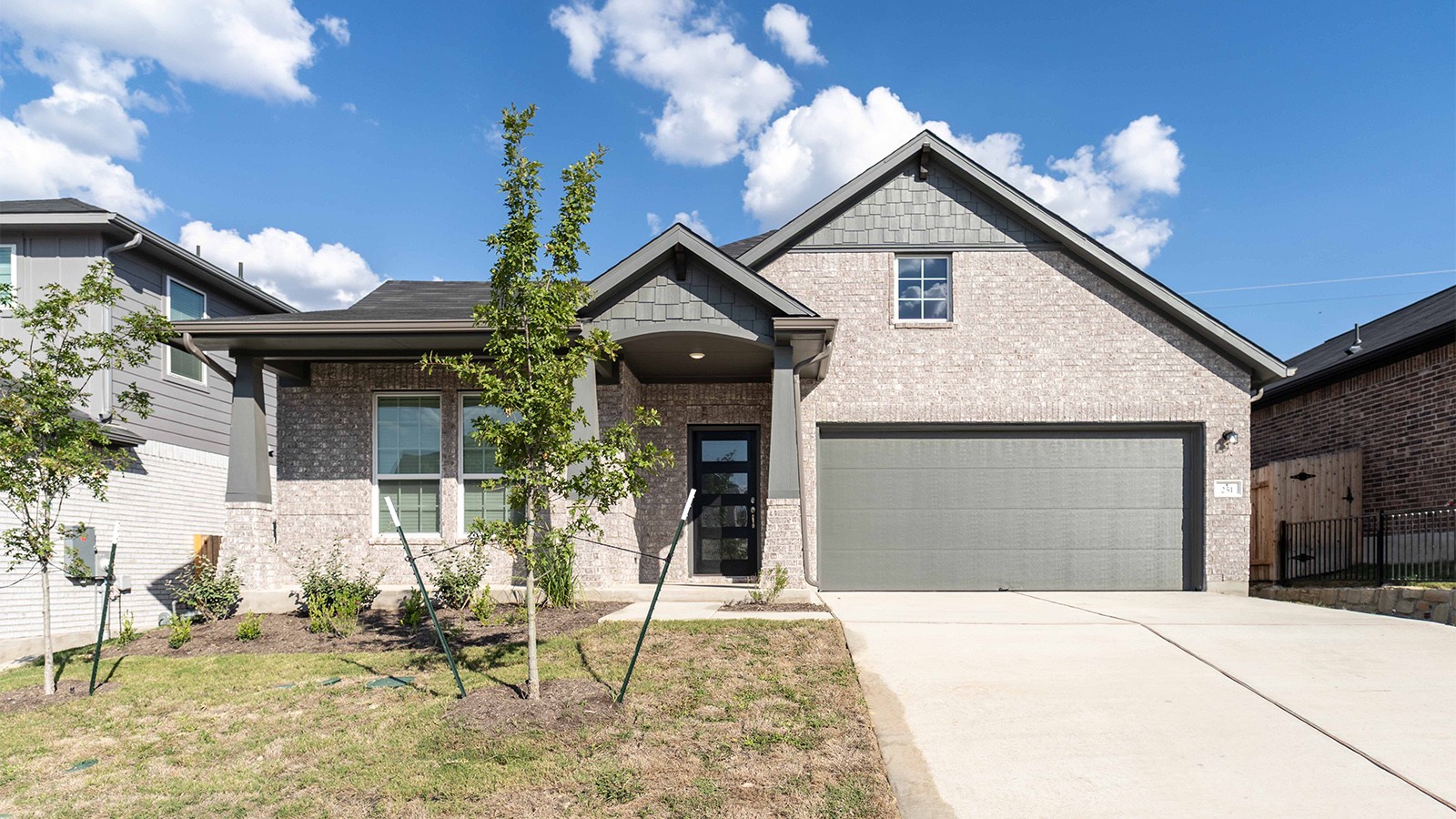 251 Grey Leaf Road Buda, TX 78610 - Photo 1 of 17 Craftsman inspired home with concrete driveway, brick siding, covered porch, and a front lawn