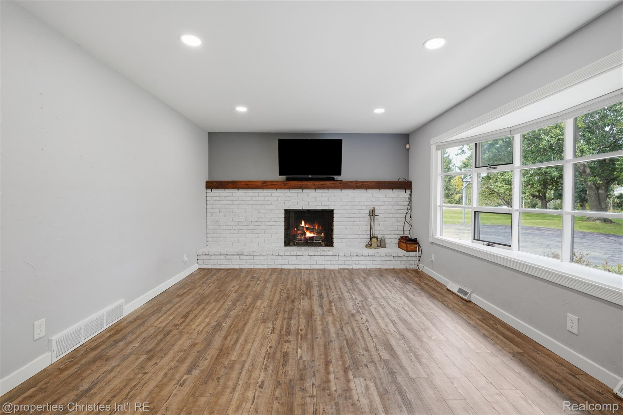 4030 Textile Road Ypsilanti, MI 48197 - Photo 7 of 58 Recessed lighting, wood-finish flooring, white brick fireplace with wood mantel, and a large bay window