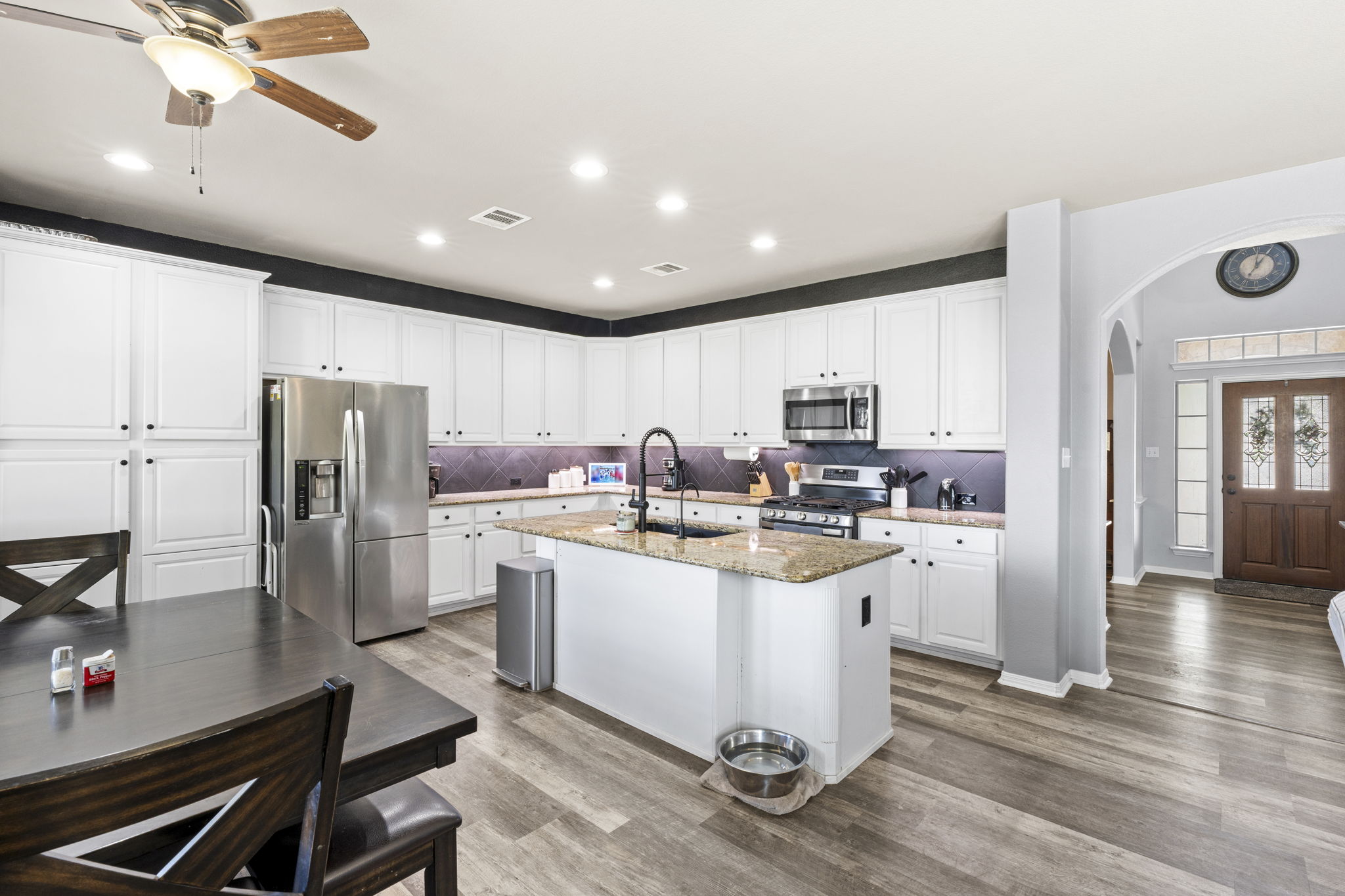 227 Sandstone Trail Buda, TX 78610 - Photo 1 of 33 Kitchen featuring white cabinetry, stainless steel appliances, a center island with a stone-finish countertop, and wood-finish flooring